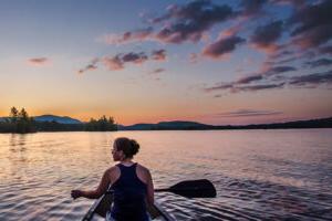 Woman paddling a canoe at sunset